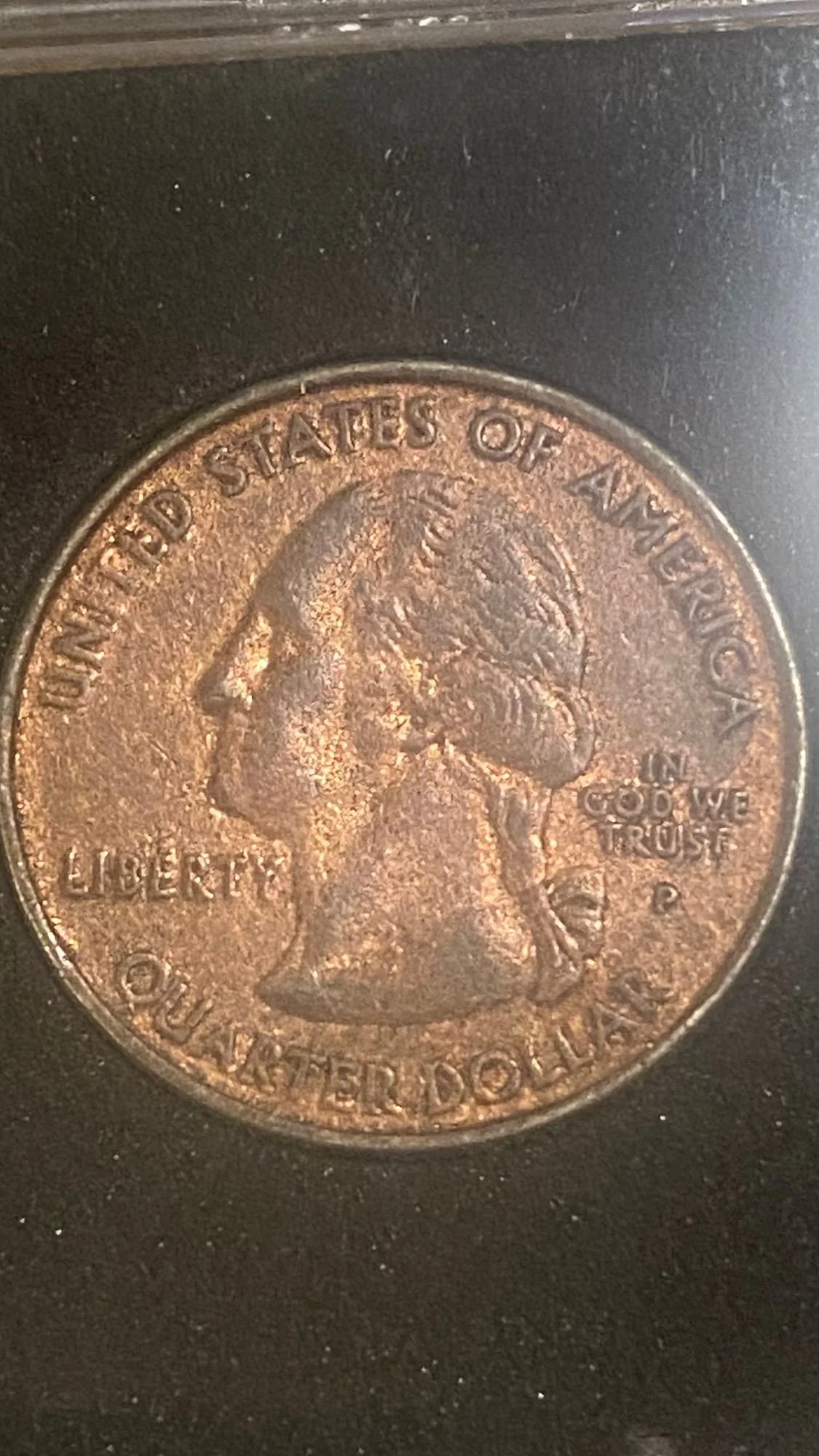 2000 quarter with missing clad layer — one side shows bright copper-orange color while the other retains normal silver-gray clad appearance